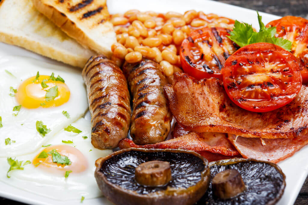 Full English breakfast with bacon, sausage, fried egg, baked beans and mushrooms.