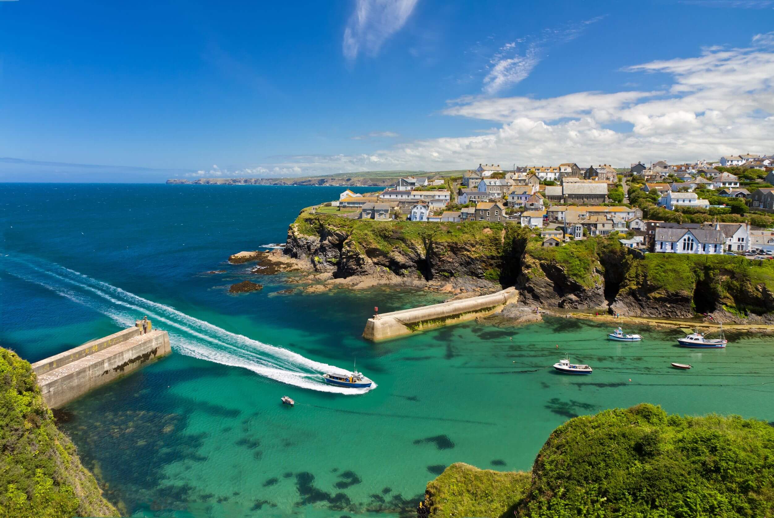 cove and harbour of port isaac with arriving ship, cornwall, england