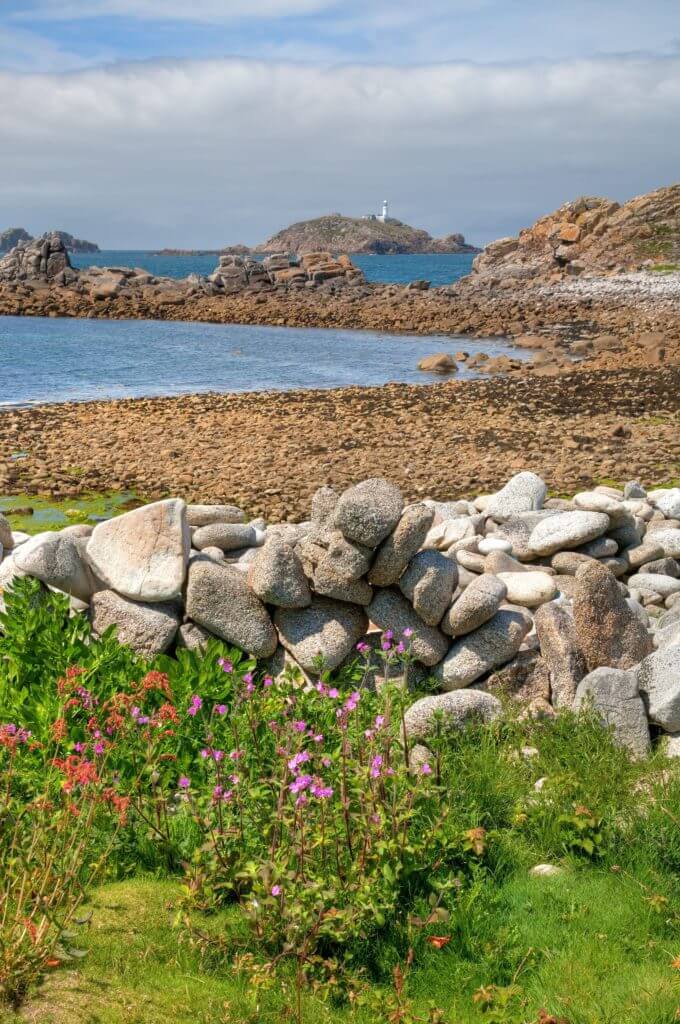 Looking over a dry-stone wall towards Round Island Lighthouse, St Martin’s, Isles of Scilly, Cornwall, England.