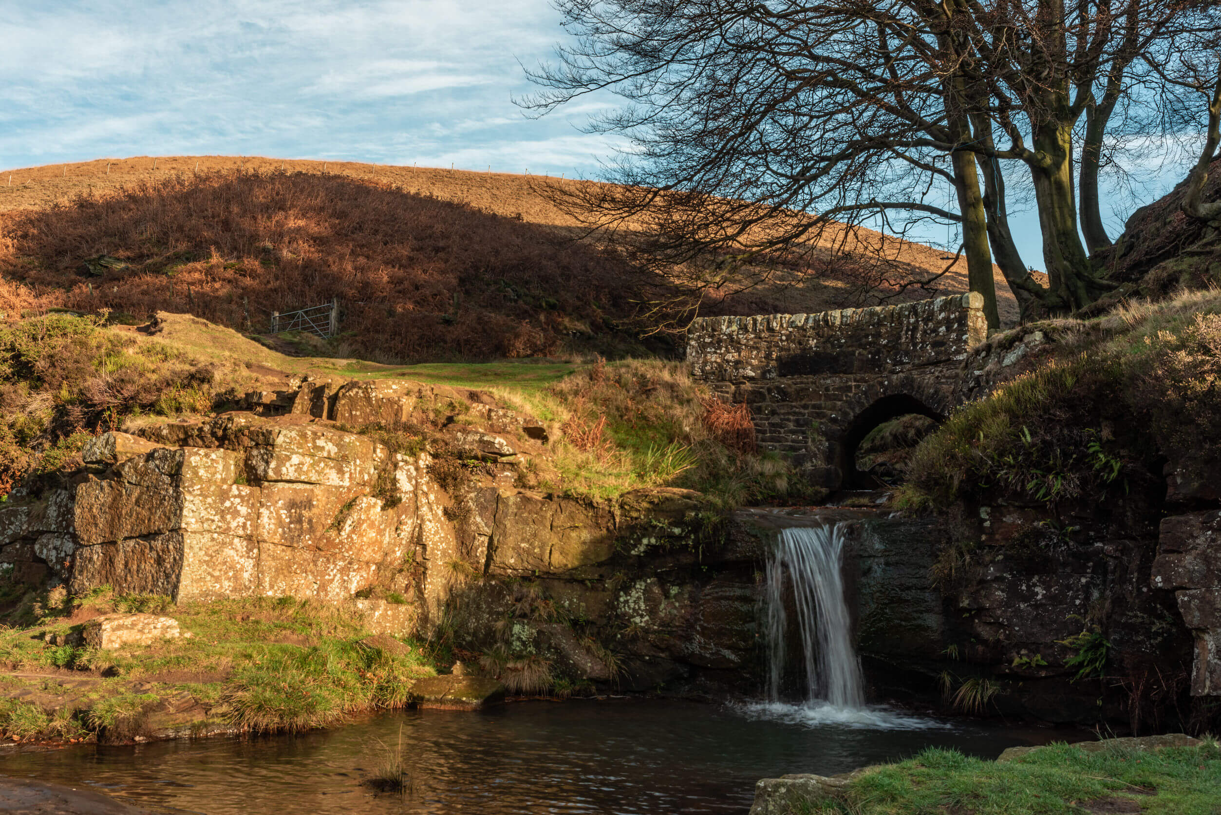 A waterfall and packhorse stone bridge at Three Shires Head in the Peak District National Park.