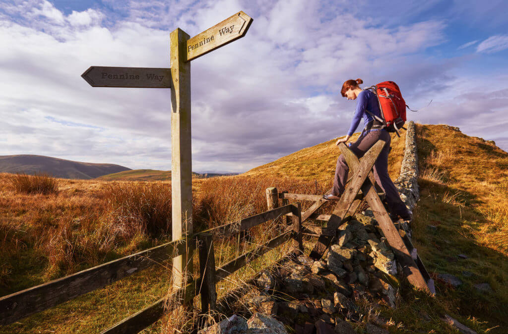 A woman crossing a stile on the Pennine Way, English Countryside walk.UK