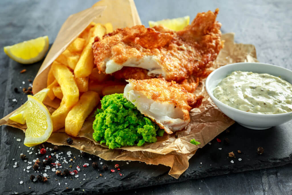 British Traditional Fish and chips with mashed peas, tartar sauce on crumpled paper