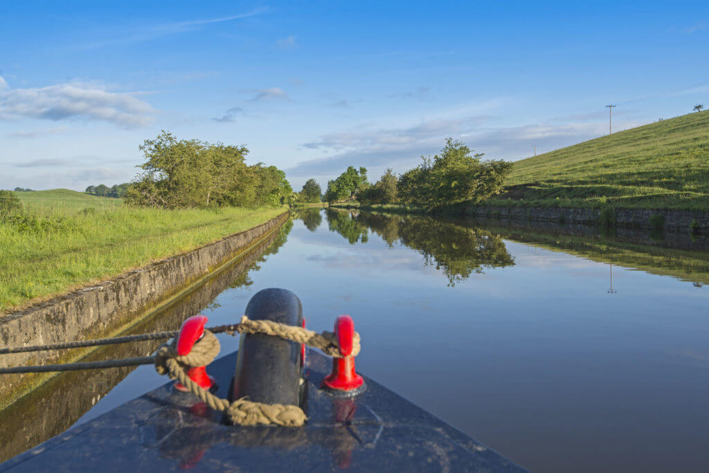 View of an English rural countryside scenery from bow of narrowboat on British waterway canal