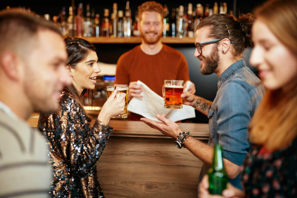 Group of friends drinking beer, chatting and having fun at pub.