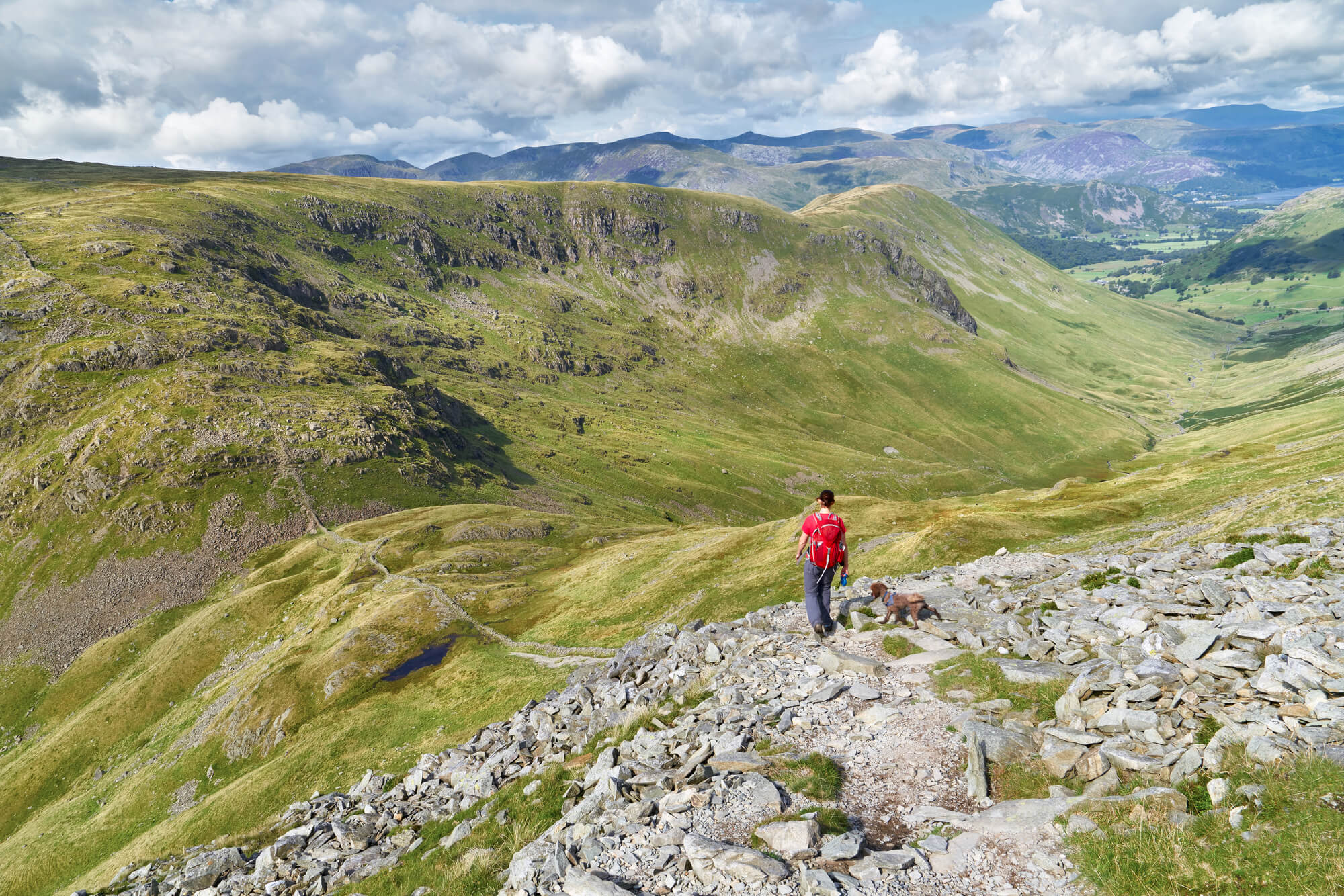 A hiker walking down from the summit of High Street, over Thornthwaite Crag and towards Pasture Beck in the English Lake District, UK.