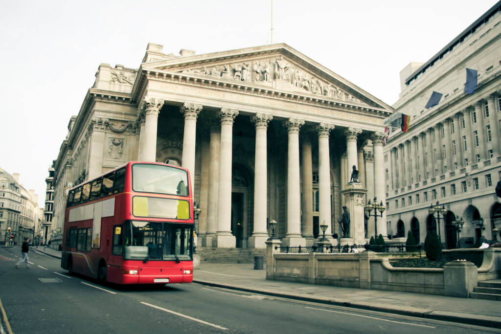 red london bus driving past the royal exchange and bank of england
