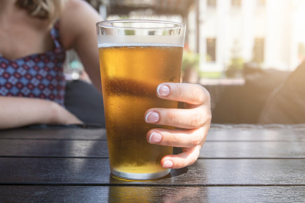 Cold, refreshing apple cider. Woman's hand with polished and varnished nails.